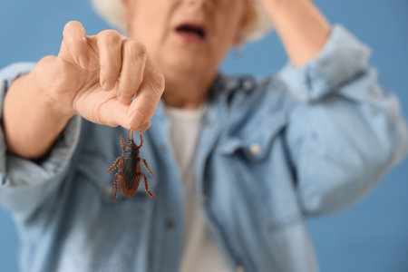Senior woman with cockroach on blue background, closeupの写真素材