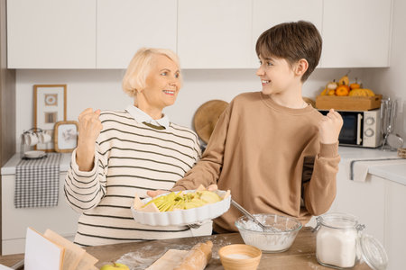 happy senior woman with her grandson making apple pie in kitchenの写真素材