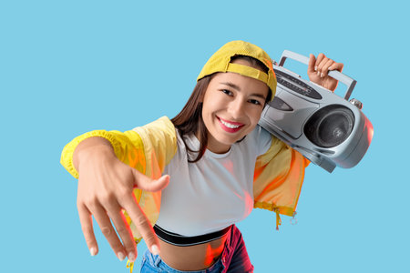 Cool female hip-hop dancer with boombox on blue background