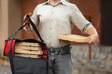 Male courier with pizza boxes in food bag on streetの写真素材