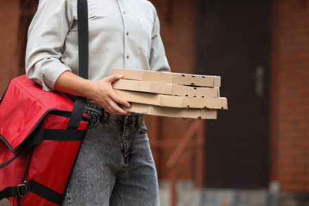 Male courier with pizza boxes and food bag on streetの写真素材