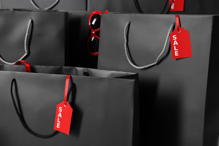 Shopping bags with tags as background, closeup. Black Friday saleの写真素材
