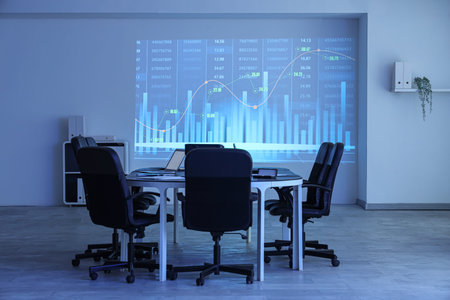 Interior of data scientist's office with workplace, laptops and diagrams projection on wall