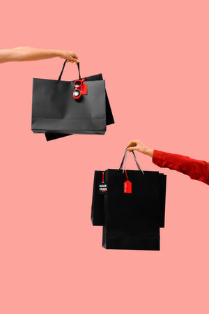 Female hands with shopping bags on pink background, closeup.の写真素材