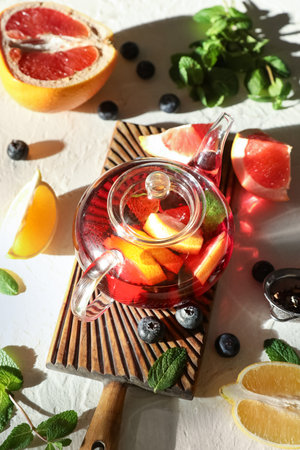 Teapot with tasty fruit tea and ingredients on white grunge backgroundの写真素材