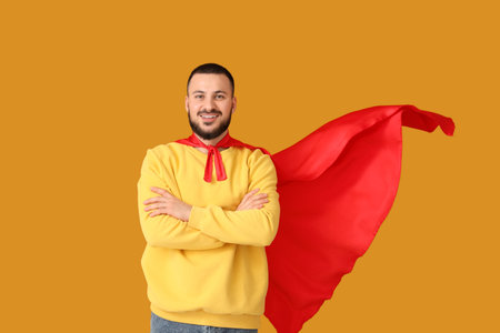 Young man with superhero cape on orange backgroundの写真素材