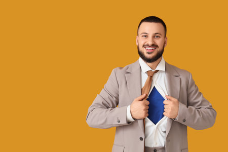 Young businessman in superhero costume under his suit on orange backgroundの写真素材