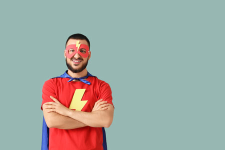 Young man dressed as superhero on green backgroundの写真素材