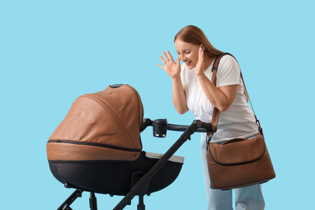 Young mother with baby stroller on blue background