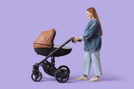Young mother with her little baby in stroller on lilac background