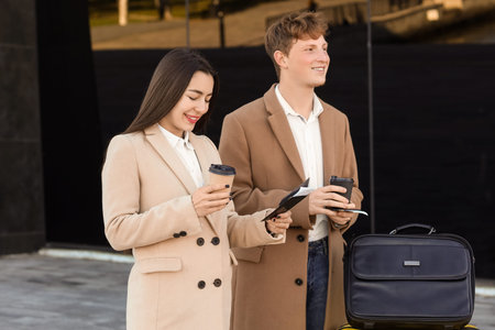 Young couple with passports and coffee cups near airport