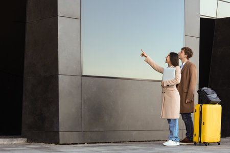 Young couple with luggage pointing at displayの写真素材