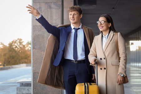 Young couple with baggage waving hand near airportの写真素材