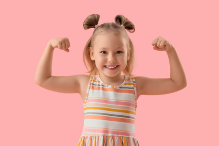 Portrait of cute little girl showing muscles on pink backgroundの写真素材