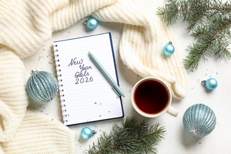 Notebook with text NEW YEAR GOALS 2026, Christmas decor and cup of tea on white grunge background