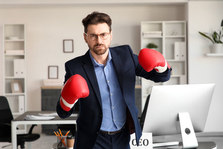 Angry businessman with boxing gloves in officeの写真素材