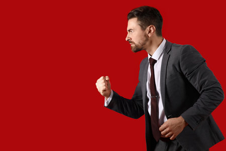 Angry businessman on red backgroundの写真素材