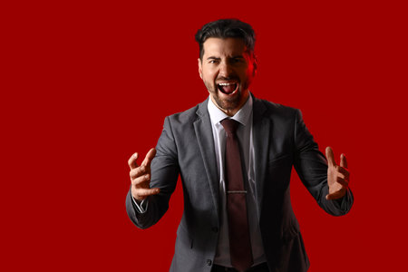 Angry businessman shouting on red background