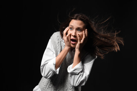 Scared young woman on black backgroundの写真素材