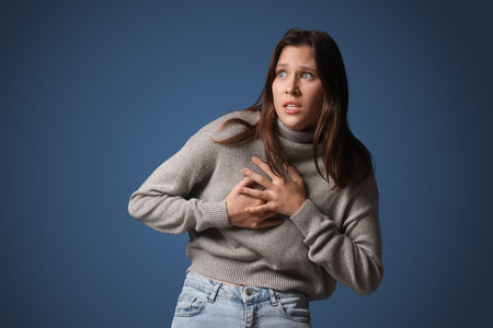 Scared young woman on dark blue background