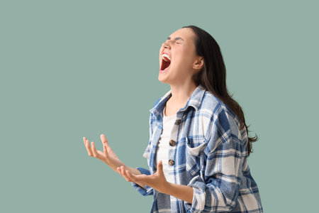 Young woman screaming on green backgroundの写真素材