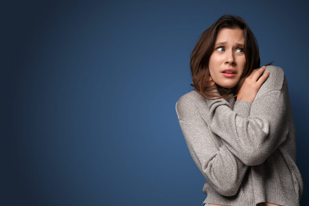Scared young woman on dark blue background