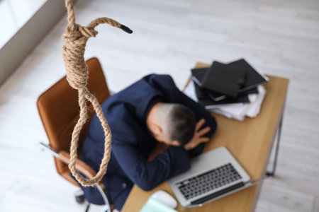 Hanging rope with loop against businessman at desk in office, closeup. International Stress...