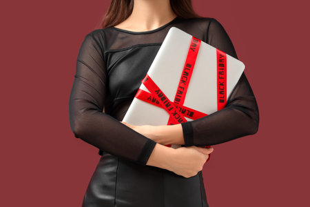 Young woman with laptop on dark red background. Black Friday sale concept