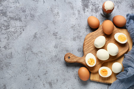 Wooden boards with fresh boiled eggs on gray grunge background