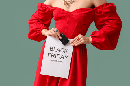 Young woman holding poster with text BLACK FRIDAY COMING SOON and credit card on turquoise backgroundの写真素材