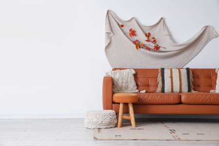 Interior of living room with autumn leaves, sofa and poufs