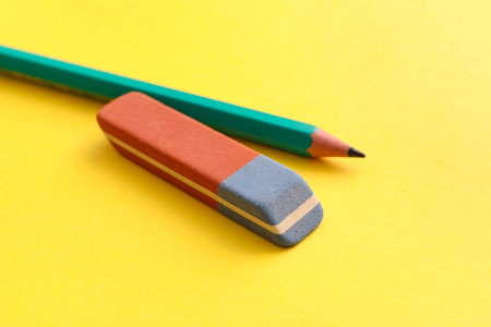 School eraser with pencil on yellow background