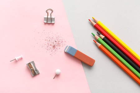 Eraser with sharpener, colorful pencils and paper clips on color backgroundの写真素材