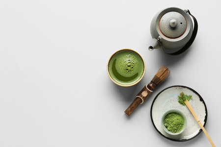Bowl of fresh matcha tea with powder, chasen, chashaku and teapot on gray backgroundの写真素材