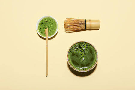 Bowl of fresh matcha tea with powder, chasen and chashaku on beige backgroundの写真素材