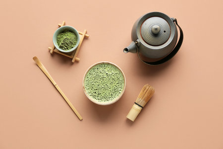 Bowl of fresh matcha tea with powder, chasen, chashaku and teapot on beige backgroundの写真素材