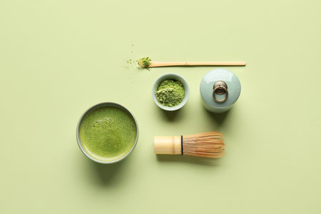 Bowl of fresh matcha tea with powder, chasen and chashaku on green backgroundの写真素材