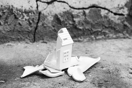 Broken house model on stone outdoors. Earthquake concept