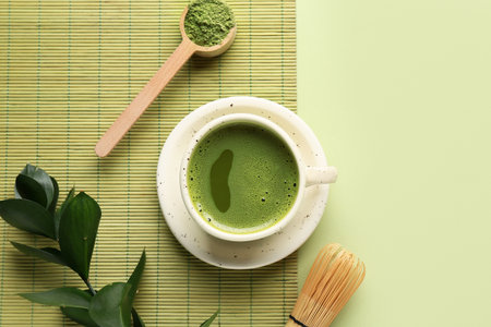 Cup of fresh matcha tea with scoop, powder and chasen on green backgroundの写真素材