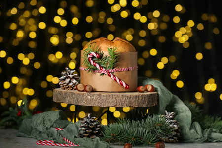 Wooden stand with Panettone and Christmas decor on dark blurred background