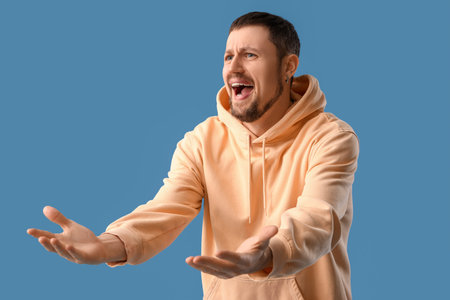 Screaming young man on blue background