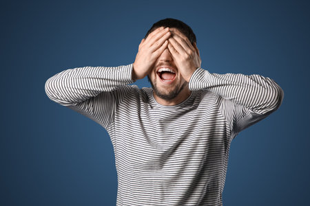 Screaming young man on dark blue backgroundの写真素材