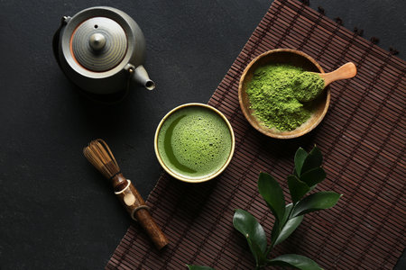 Composition with bowl of matcha tea and green twig on black grunge backgroundの写真素材