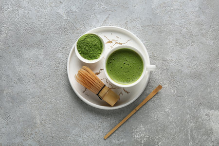 Tray with cup of matcha tea and chasen on gray grunge backgroundの写真素材