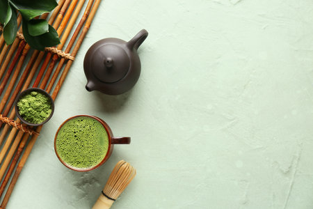 Composition with bamboo mat, bowl of matcha tea and teapot on green grunge backgroundの写真素材