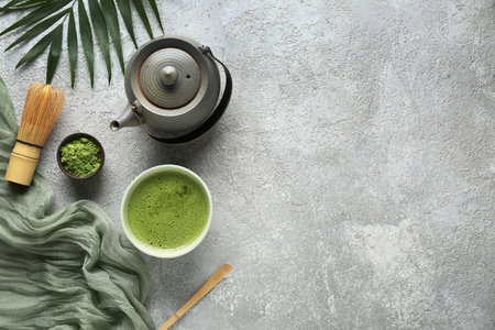 Composition with bowl of matcha tea, teapot and tropical leaf on gray grunge backgroundの写真素材
