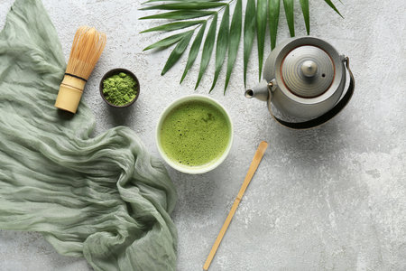 Composition with bowl of matcha tea, teapot and tropical leaf on gray grunge backgroundの写真素材