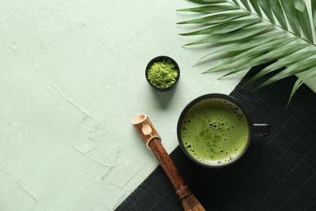 Composition with wicker mat, bowl of tasty matcha tea and tropical leaf on green grunge background, closeupの写真素材