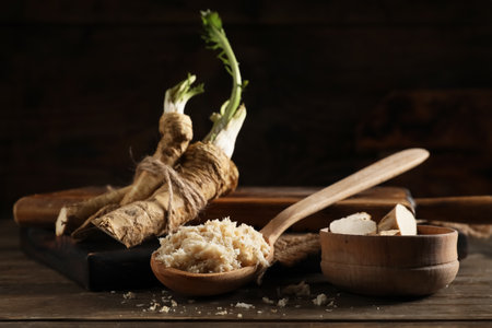 Wooden spoon with horseradish sauce, roots and slices on wooden backgroundの写真素材