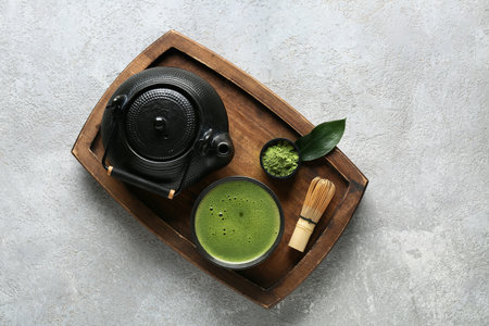 Wooden tray with bowl of matcha tea, teapot and chasen on gray grunge backgroundの写真素材